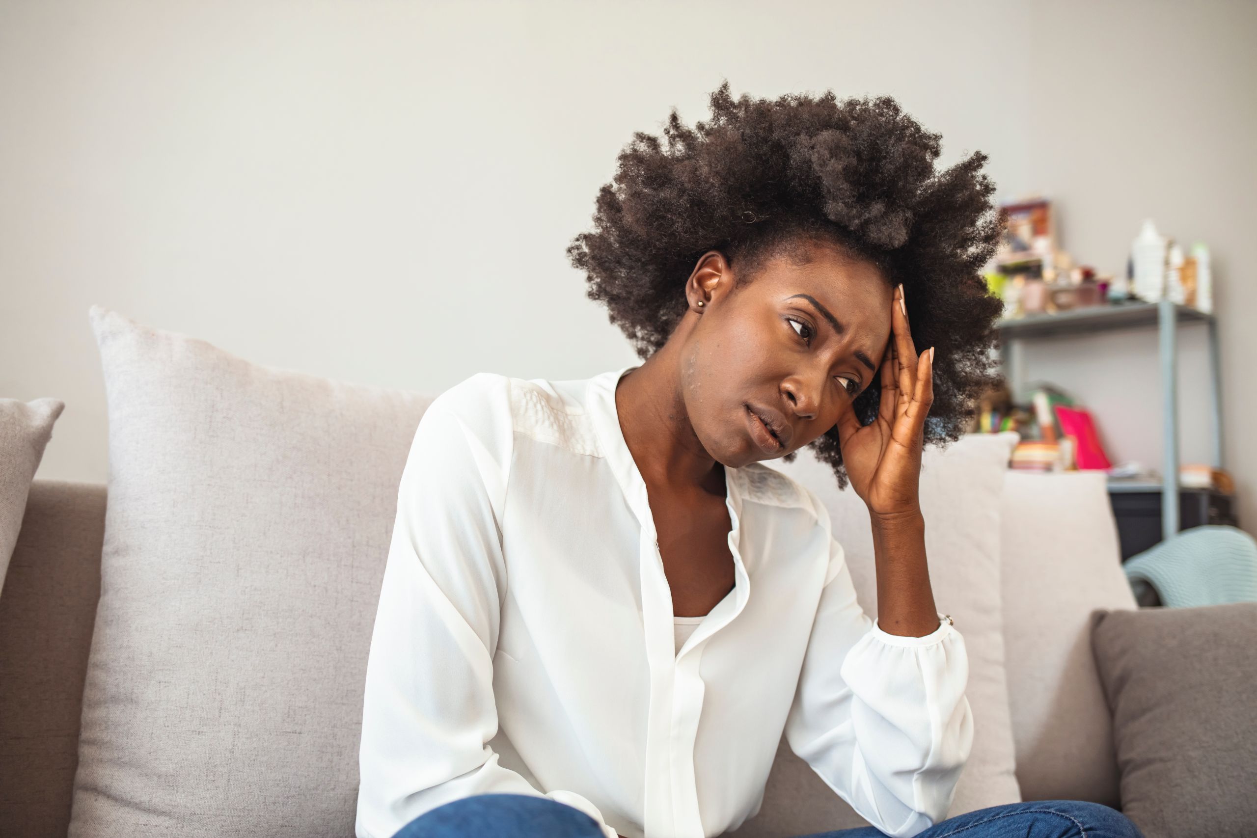 Close up african female sit on couch feels unhappy desperate thinking about personal difficulties mental health problems, 30s sad woman need psychological support goes through divorce break up concept
