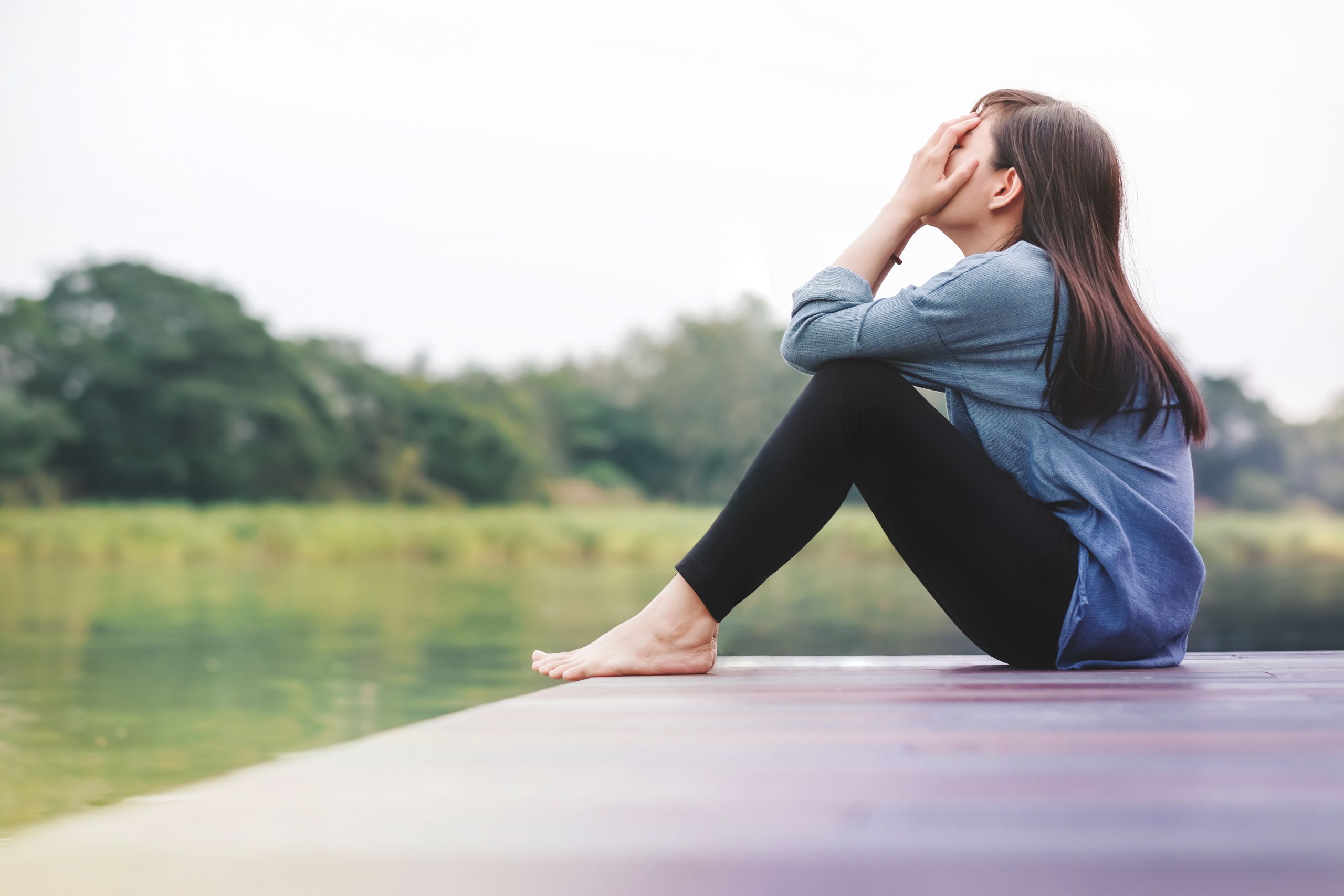 Bad Day Concept. Sadness Woman Sitting by the River on Wooden Patio Deck. Faceless with Full Length Body, Side View