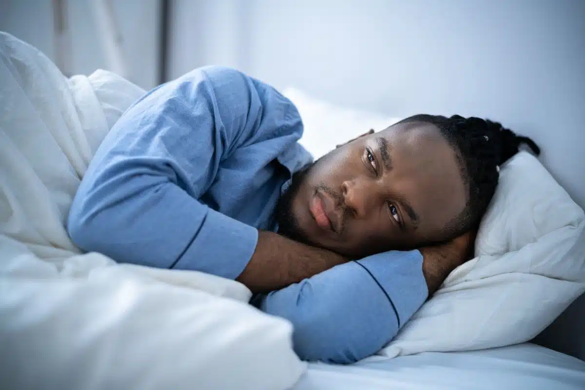 man struggling to fall asleep because of insomnia symptoms